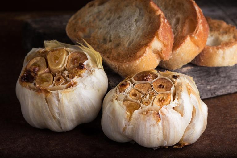 heads of roasted garlic with slices of toasted bread.
