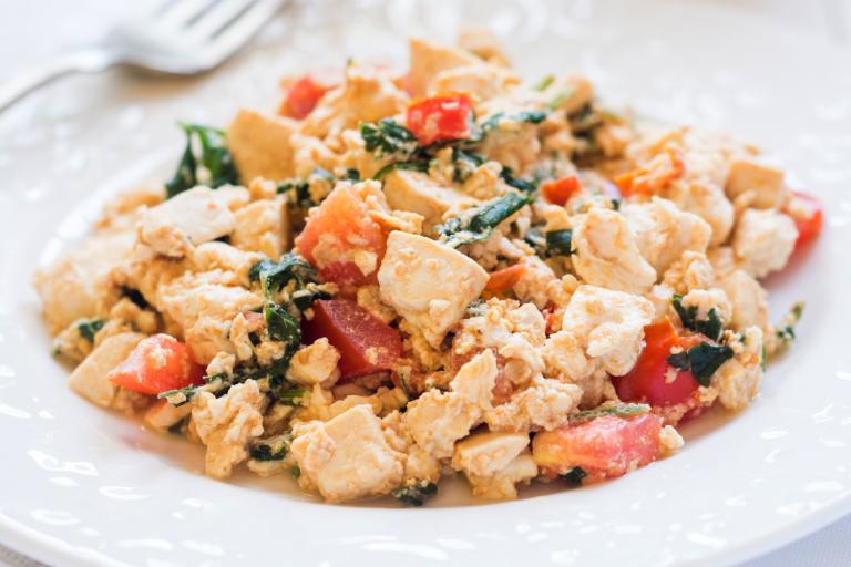 a plate of scrambled tofu with greens and tomatoes
